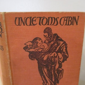 May include: An orange book cover with the title "Uncle Tom's Cabin" in black lettering. The cover features a black and white illustration of a man carrying a woman.