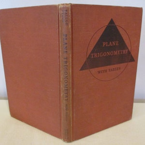 May include: A brown book with the title "Plane Trigonometry with Tables" on the spine and cover. The cover features a black triangle inside a circle.