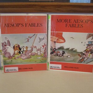 May include: Two vintage children's books, "Aesop's Fables" and "More Aesop's Fables," with orange covers and illustrations. The covers feature colorful drawings of animals and scenes from the fables. The books are wrapped in clear plastic.