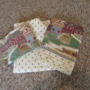 May include: Four fabric panels with a farmhouse theme. The panels feature a white background with a small yellow flower pattern. The panels also feature a red barn with a blue roof and a water wheel. The text "General Store" is printed on the barn.