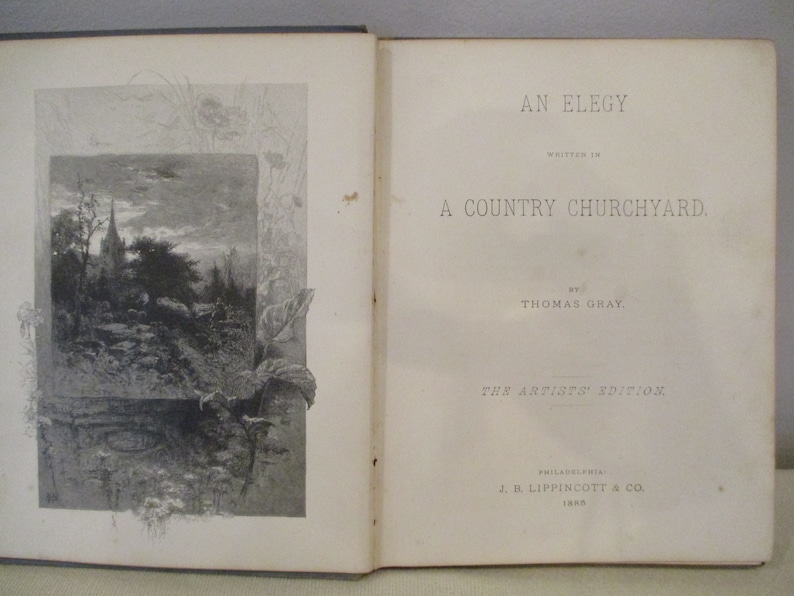 May include: An open book with a black and white illustration of a country churchyard on the left page. The right page has the title "An Elegy Written in a Country Churchyard" by Thomas Gray. The book is from the Artists' Edition, published by J.B. Lippincott & Co. in 1888.