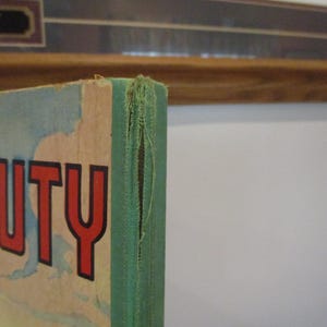 May include: Close-up of a vintage book cover with the word "BEAUTY" in large red letters. The cover has a distressed, aged appearance with a green spine and visible wear and tear.