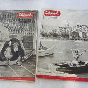 以下が含まれることがあります： 1958年8月号のドイツの雑誌「デア・シュピーゲル」のヴィンテージ版2冊。左側の雑誌の表紙には、ロッキングホースに乗ったチンパンジーが写っている。右側の雑誌の表紙には、街を背景に湖のボートに乗った女性が写っている。左側の表紙のテキストは「Jetzt gibt es det Watti!」、右側の表紙のテキストは「Heist U.a.b.s.  D.y.n.  F.i.n.e  V.a.k.a.n.t.e  (G.e.b.a.u.d.t.!)?」となっている。