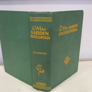 Puede incluir: Un libro de tapa dura verde titulado "The Wise Garden Encyclopedia" con letras doradas. El libro est&aacute; ilustrado y tiene un dise&ntilde;o de &aacute;rbol dorado en el lomo.