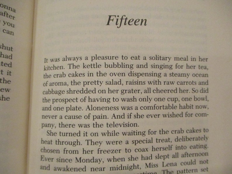 Puede incluir: Un primer plano de una p&aacute;gina de libro con el t&iacute;tulo "Fifteen" y texto sobre una mujer que disfruta de una comida solitaria en su cocina. El texto describe la tetera hirviendo, las tartas de cangrejo en el horno y una ensalada con pasas y col rallada.