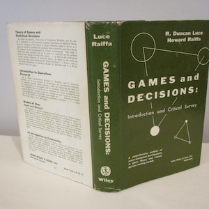 May include: A hardcover book titled "GAMES and DECISIONS: Introduction and Critical Survey" by R. Duncan Luce and Howard Raiffa. The book has a green cover with white text and geometric shapes. The spine reads "GAMES and DECISIONS" vertically.