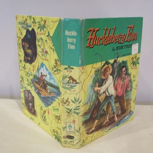 Puede incluir: Un libro antiguo de tapa dura titulado "Huckleberry Finn" de Mark Twain. La portada presenta un fondo verde con ilustraciones de dos niños pescando y un fondo amarillo con ilustraciones de una escena de río.