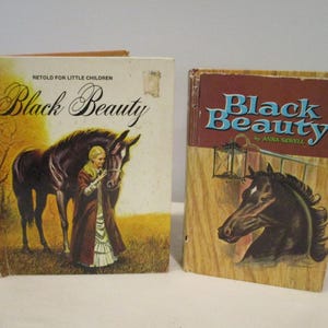 May include: Two vintage copies of "Black Beauty" by Anna Sewell. One book features a woman and a black horse on the cover, with the title in elegant script. The other book has a horse head illustration and the title in blue.
