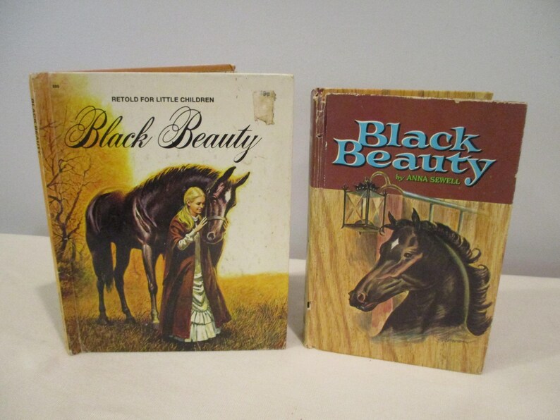 May include: Two vintage copies of "Black Beauty" by Anna Sewell. One book features a woman and a black horse on the cover, with the title in elegant script. The other book has a horse head illustration and the title in blue.