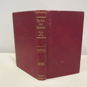 May include: A red hardcover book titled "Practical Shop Mathematics" by Wolfe and Phelps. The book is a revised edition and is volume I, Elementary.