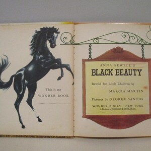 May include: Open book with a black horse illustration on the left page and text on the right. The book is titled "Black Beauty" by Anna Sewell, retold for children. The book is part of the Wonder Books series.