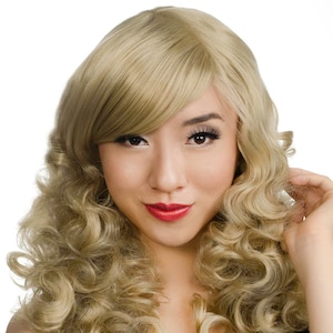 Pode incluir: Uma peruca loira com cachos longos e soltos e uma franja lateral. A peruca &eacute; estilizada em um estilo vintage e glamouroso.