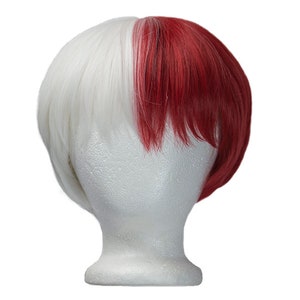 May include: A two-toned wig, featuring a striking contrast of white and red. The wig is styled with a short, layered cut, with the hair divided into two distinct sections of color. The wig is displayed on a white mannequin head.