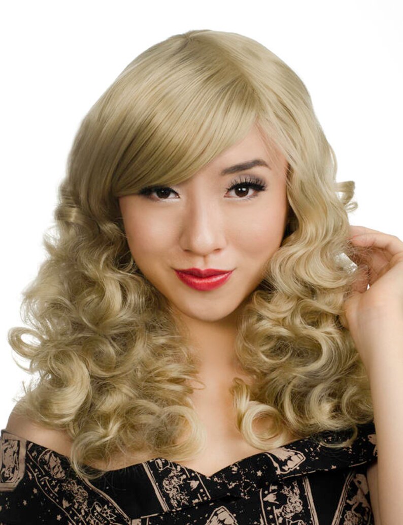 Pode incluir: Uma peruca loira com cachos longos e soltos e uma franja lateral. A peruca &eacute; estilizada em um estilo vintage e glamouroso.