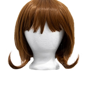 May include: A brown wig with bangs and a bob style. The wig is on a white mannequin head.
