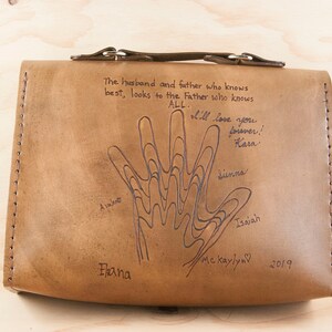 May include: A brown leather bag with a handprint design and the text "The husband and father who knows best, looks to the Father who knows ALL. I'll love you forever! Kara Sienna Isaiah Me Kaylyn 2019 Elana"