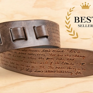 Puede incluir: Correa de guitarra de cuero marrón con una cita escrita a mano: "who matter don't mind. -Dr. S.  We are the change -Pe Do not go where the path may lead,  to the other side of the clouds. -JZ The main thing is to Life isn't about waiting for"