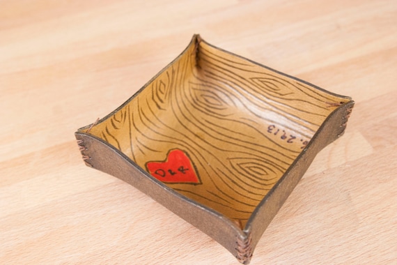 A handcrafted leather valet tray with woodgrain texture and custom personalization — the kind of desk or nightstand piece that actually gets used every day and looks like it cost twice as much.