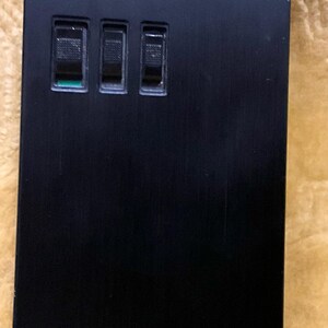 Puede incluir: Un reproductor de casetes Sony negro con tres botones y un logotipo plateado.