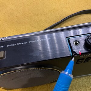 Puede incluir: Un sistema de altavoces est&eacute;reo alimentado por Sony negro con un borde plateado y un altavoz grande. El sistema tiene una perilla de volumen, una perilla de sintonizador y un interruptor de encendido. El texto "POWERED STEREO SPEAKER SYSTEM SRF-8W" est&aacute; impreso en la parte frontal del sistema.