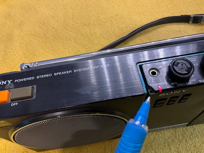 Puede incluir: Un sistema de altavoces est&eacute;reo alimentado por Sony negro con un borde plateado y un altavoz grande. El sistema tiene una perilla de volumen, una perilla de sintonizador y un interruptor de encendido. El texto "POWERED STEREO SPEAKER SYSTEM SRF-8W" est&aacute; impreso en la parte frontal del sistema.