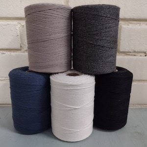 May include: Five spools of cotton cord in different colors: gray, black, white, navy blue, and dark gray. The spools are stacked on top of each other.
