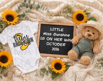 May include: A white baby bodysuit with a yellow footprint graphic and the text Baby Anderson, a black chalkboard with the text Little Miss Sunshine IS ON HER WAY OCTOBER 2026, and a brown teddy bear wearing green overalls and a straw hat.