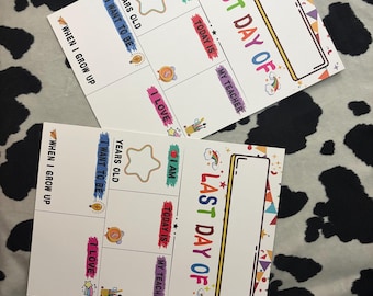 May include: Two white rectangular signs featuring colorful graphics and text. One sign reads FIRST DAY OF and the other reads LAST DAY OF. Both include sections for I AM, YEARS OLD, TODAY IS, MY TEACHER, I LOVE, I WANT TO BE, and WHEN I GROW UP.