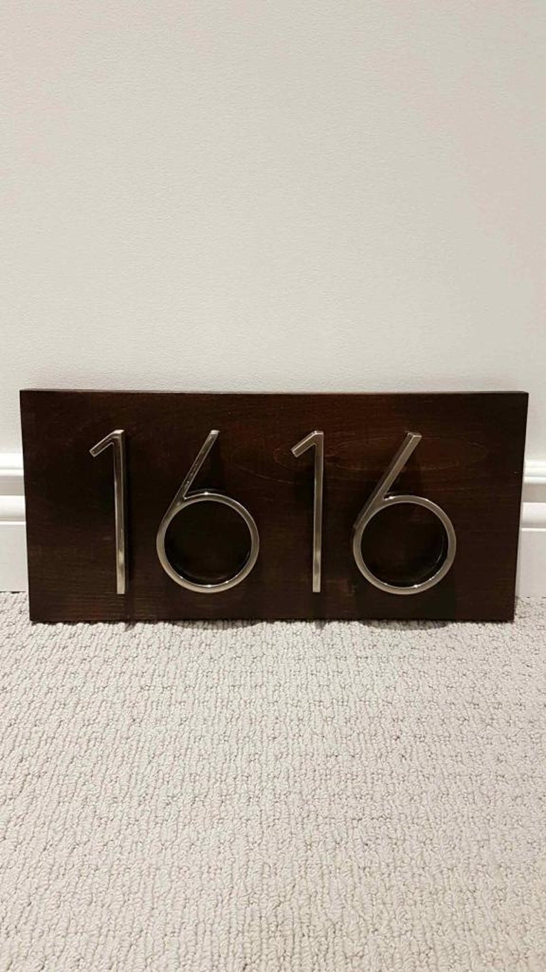 May include: A dark brown wooden plaque with the number 1616 in silver metal lettering.