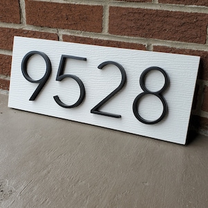 May include: White house number sign with black raised numbers 9528.