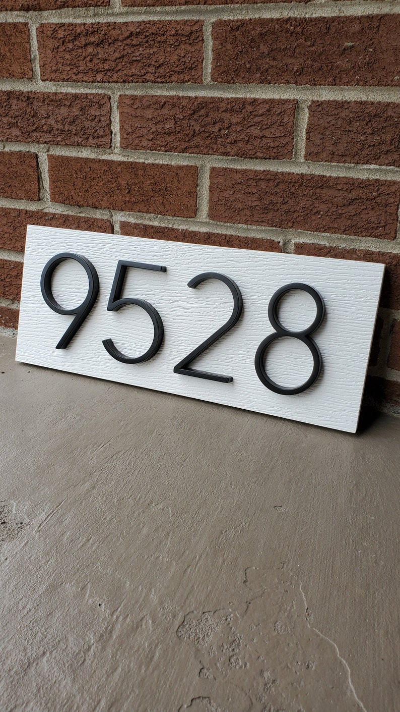 May include: White house number sign with black raised numbers 9528.