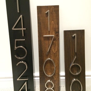 May include: Three wooden house number signs with silver metal numbers. The first sign is black with the numbers 14524. The second sign is brown with the numbers 1708. The third sign is brown with the numbers 160.