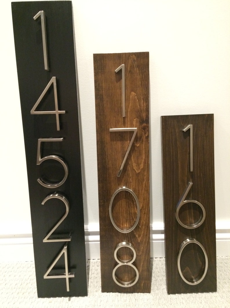 May include: Three wooden house number signs with silver metal numbers. The first sign is black with the numbers 14524. The second sign is brown with the numbers 1708. The third sign is brown with the numbers 160.