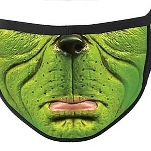 May include: Green face mask with a cartoon-like face, featuring a large nose, wrinkled forehead, and a frowning mouth. The mask is made of a soft, breathable fabric and has adjustable ear loops.