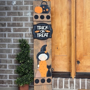May include: A wooden Halloween sign with a witch, black cat, and the words "Trick or Treat." The sign features an orange pumpkin, a cauldron, and a witch with a broom. The sign is made of wood and has a rustic appearance.