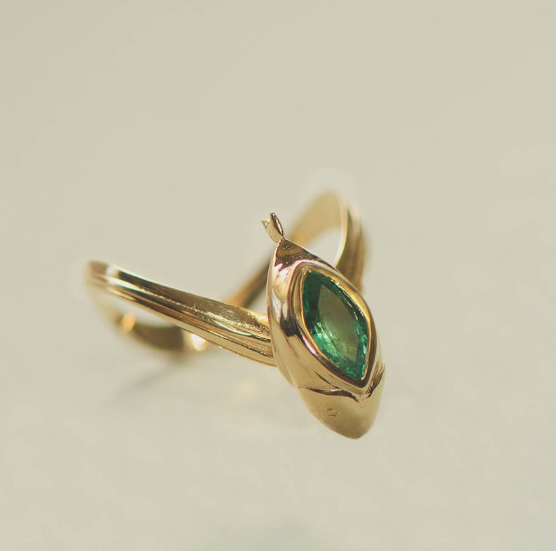 Puede incluir: Un anillo de oro con una esmeralda de forma marquesa engastada en garras.