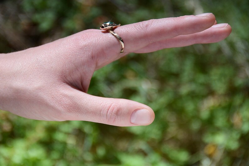 Puede incluir: Un anillo de oro con una piedra preciosa verde en forma de tortuga.
