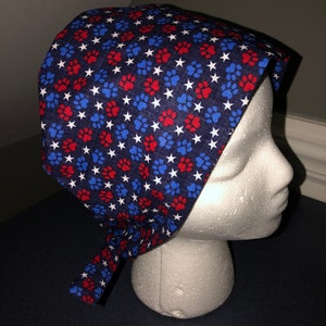 May include: A blue scrub hat with a white background and red and blue paw prints and white stars.