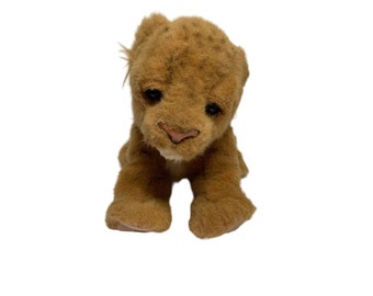May include: A brown plush lion cub toy with a white chest and a brown nose. The toy is sitting on a white background.