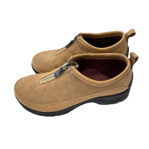 May include: Tan suede zippered slip-on shoes with a quilted pattern and black rubber soles.