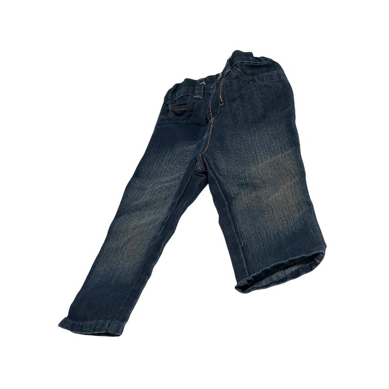 May include: Dark blue denim pants with a faded wash. The pants have a classic five-pocket design, a button and zipper closure, and a slightly worn appearance. The stitching is a contrasting light brown color.
