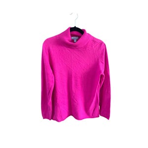 Puede incluir: Un jersey de cuello alto de color rosa brillante con mangas largas.