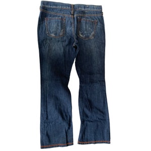 Op de afbeelding: Een paar blauwe denim jeans met een bootcut pijp. De jeans heeft een vervaagde look en oranje stiksels.