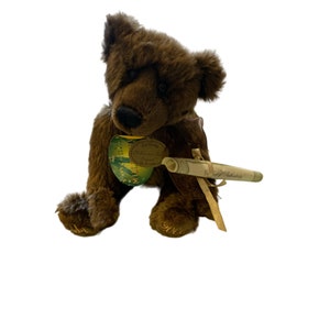 May include: A brown teddy bear with a green and gold tag that says "20th Anniversary Commemorative Bear No. 1947". The bear is holding a scroll that says "With love and fidelity".