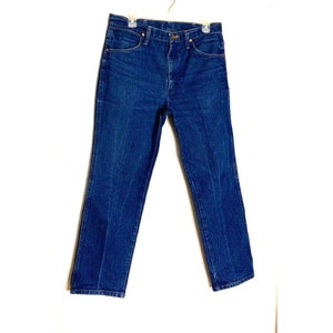 May include: A pair of dark blue denim jeans with a button fly and belt loops.
