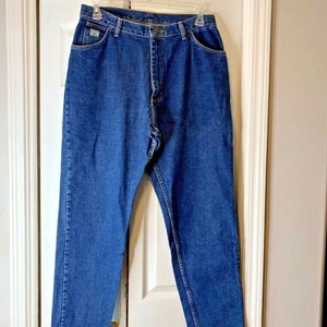 May include: A pair of blue denim jeans with a straight leg fit. The jeans have a button fly and belt loops.