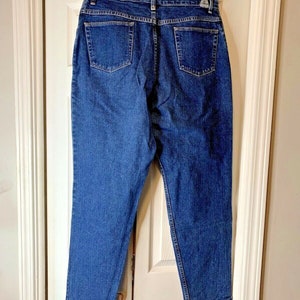 May include: A pair of dark blue denim jeans with a straight leg fit. The jeans have a classic five-pocket style and a button fly.