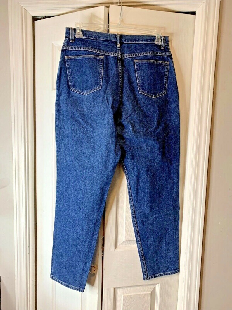 May include: A pair of dark blue denim jeans with a straight leg fit. The jeans have a classic five-pocket style and a button fly.