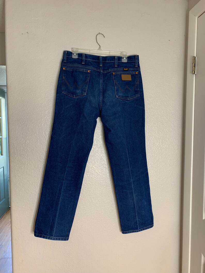 May include: A pair of blue denim jeans with a brown leather patch on the back pocket.