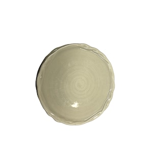 May include: A round, off-white ceramic plate with a spiral design in the center. The plate has a wavy, irregular edge. The plate is set against a white background.